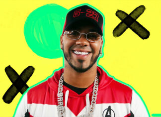 Anuel Aa is smiling with a bright yellow background and artistic crosses, HD Desktop Wallpaper