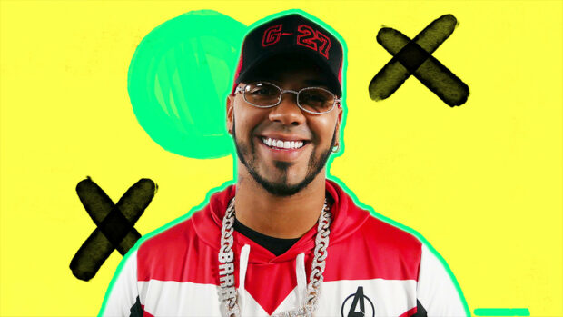 Anuel Aa is smiling with a bright yellow background and artistic crosses, HD Desktop Wallpaper