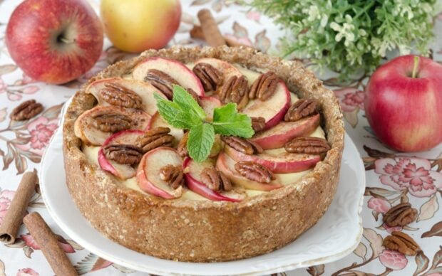 A pie with apple slices and pecans garnished with fresh mint leaves on a floral tablecloth, HD Desktop Wallpaper