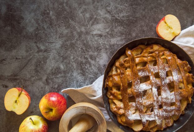 A freshly baked apple pie with lattice crust and sliced apples on a rustic table, HD Desktop Wallpaper