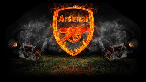 Fiery Arsenal logo with two smoking cannons on a dark grassy background