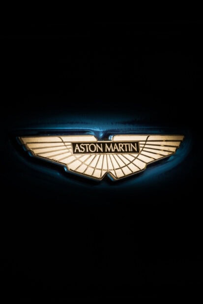 Close up of Aston Martin emblem on dark background showing luxury car logo