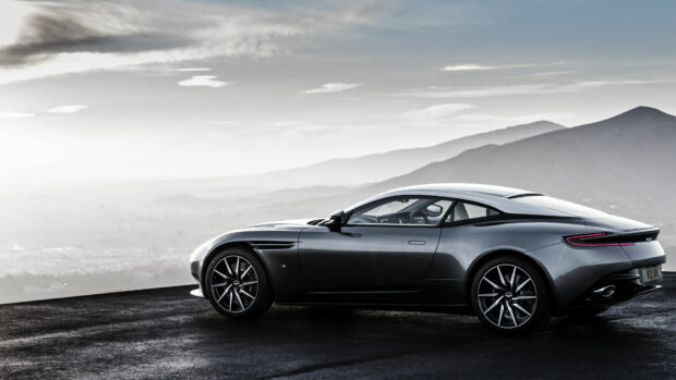 Sleek Aston Martin sports car parked on a mountain road under a cloudy sky