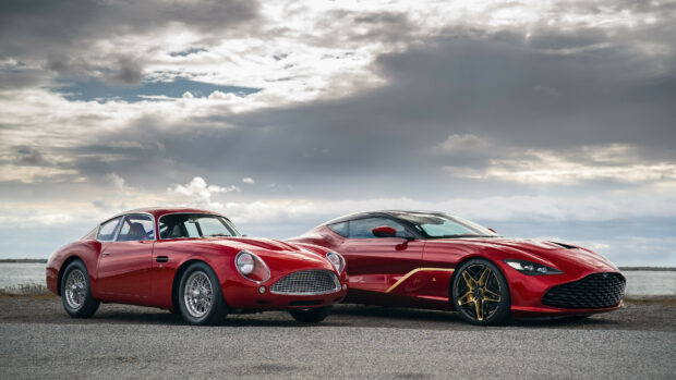 Two red Aston Martin classic and modern cars parked side by side on a cloudy day