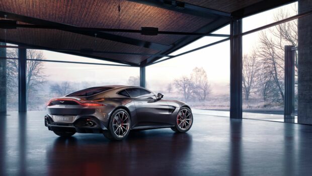 A sleek Aston Martin parked inside a modern glass garage with a winter landscape outside