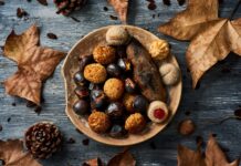 A plate filled with roasted chestnuts and assorted sweet treats surrounded by dry autumn leaves, 2K Desktop Wallpaper