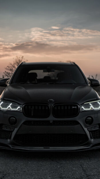 A BMW X5 is parked on the road with headlights on during sunset, 4K Phone Wallpaper