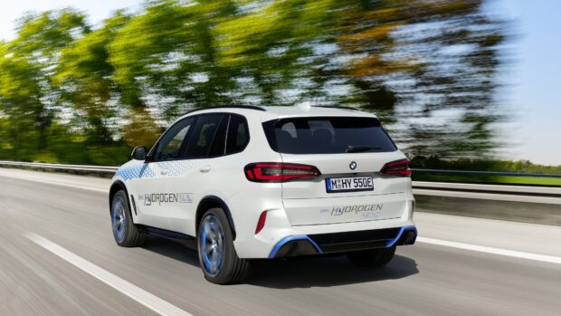 A BMW X5 hydrogen fuel cell SUV drives swiftly on a highway with greenery, 4K Desktop Wallpaper