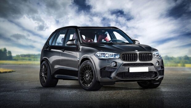 A sleek BMW X5 is parked on an open road under a cloudy sky, 2K Desktop Wallpaper