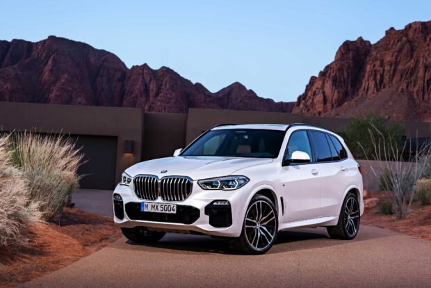 A white BMW X5 is parked on a desert road with mountains in the background, HD Desktop Wallpaper