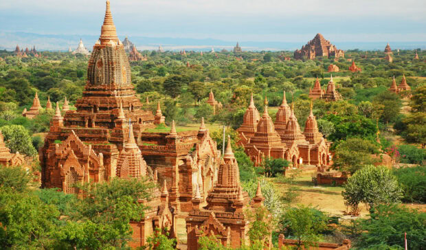 Ancient Bagan architecture surrounded by lush greenery in a vast landscape