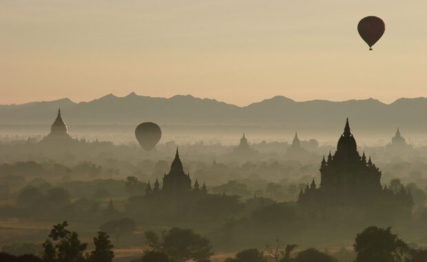 Ancient temples in Bagan with hot air balloons at sunrise in a misty landscape