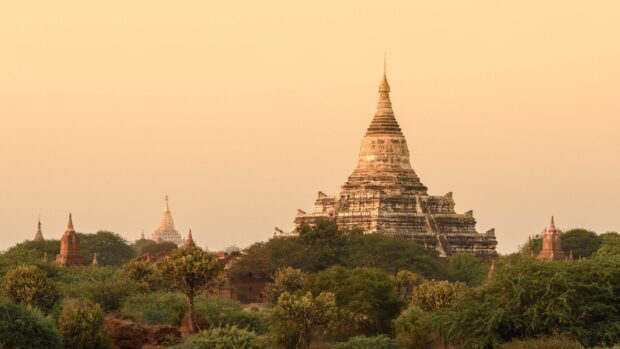 Ancient Bagan temple surrounded by lush greenery under warm light