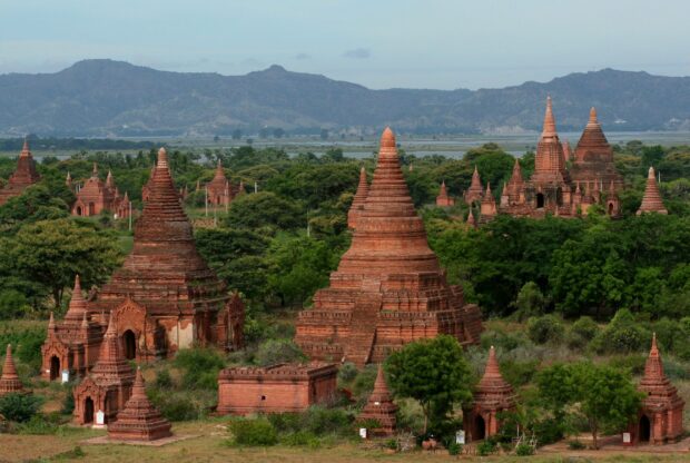 Ancient Bagan temples surrounded by greenery and mountains in the background