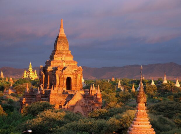 Ancient Bagan temples surrounded by greenery under a cloudy sky