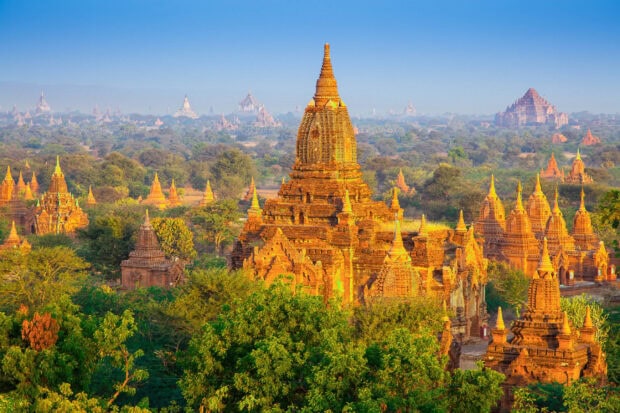 Ancient Bagan temples surrounded by lush greenery and clear blue sky in Myanmar