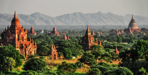 Ancient temples and pagodas in Bagan surrounded by lush greenery and distant mountains