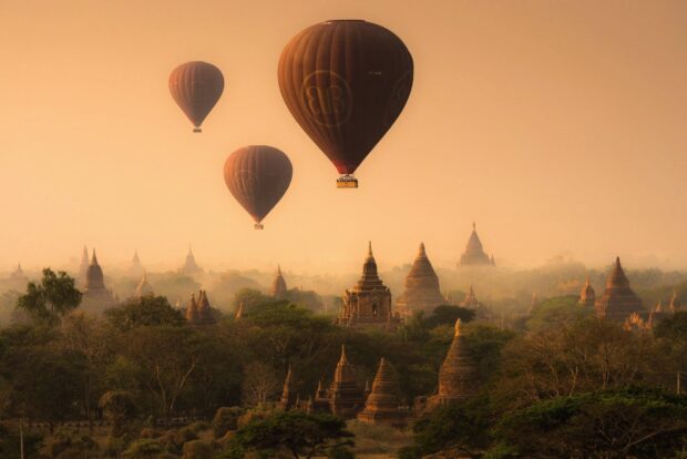 Hot air balloons flying over ancient Bagan temples at sunrise in Bagan