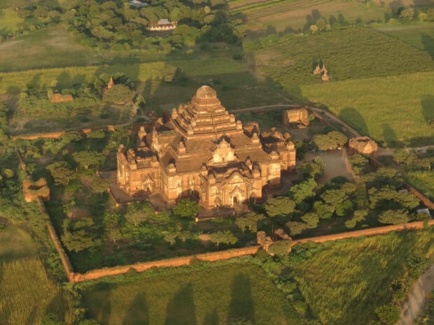 Ancient temple architecture in Bagan surrounded by lush greenery and fields