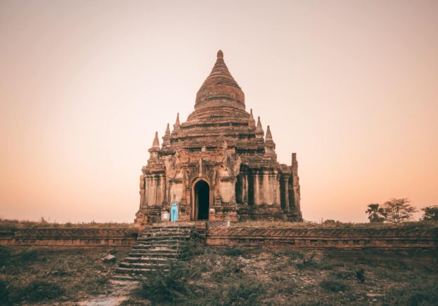 A woman exploring ancient Bagan architecture at sunset with warm sky background
