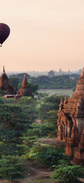 Ancient Bagan architecture and green landscape with a hot air balloon in the sky
