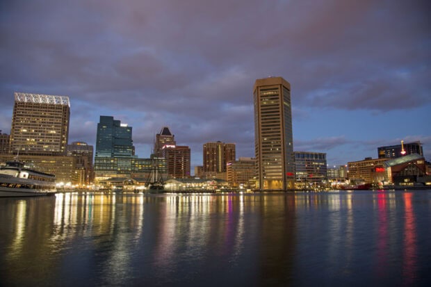 Baltimore skyline at dusk with clear reflections on the water and illuminated buildings