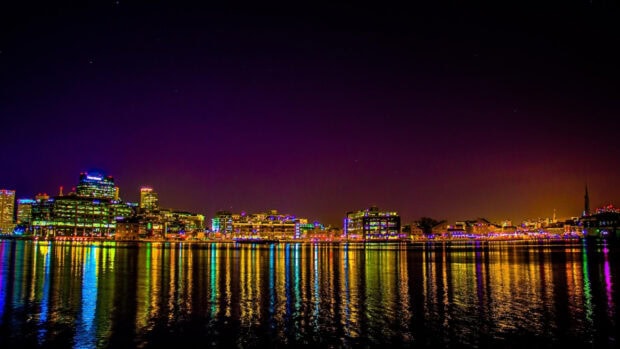 Baltimore skyline brightly lit at night with colorful reflections on the water