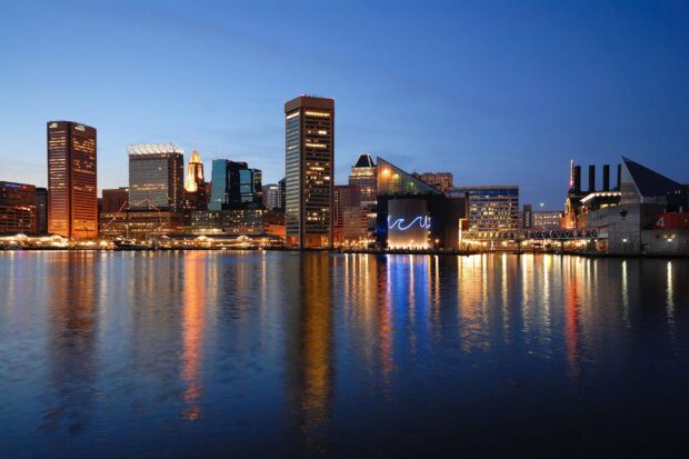 The Baltimore skyline reflects beautifully on the calm water during twilight with clear sky
