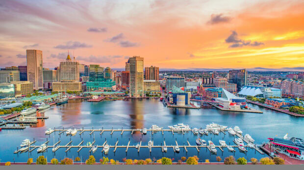 Baltimore skyline viewed at sunset with boats docked in the harbor and colorful sky