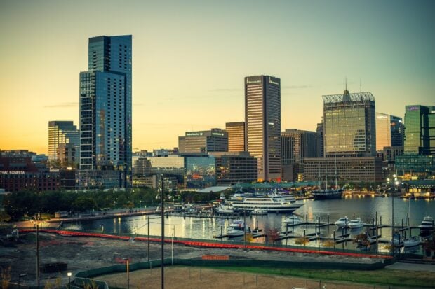 Baltimore skyline viewed at sunset with boats docked in the harbor and tall buildings in the background