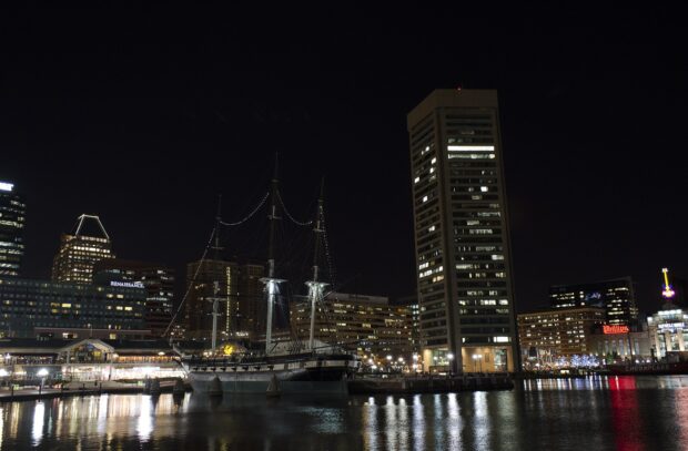 Historic Baltimore skyline at night with illuminated buildings reflecting on water