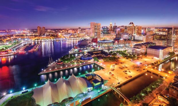 A vibrant Baltimore skyline at night with illuminated waterfront and city buildings
