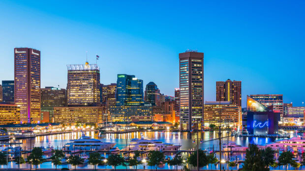 A vibrant Baltimore skyline featuring high rise buildings and harbor at dusk with clear blue sky