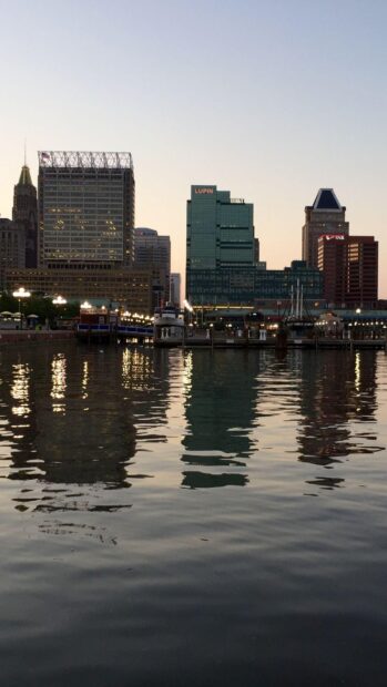 Evening view of Baltimore skyline reflecting on water with tall buildings and calm sky