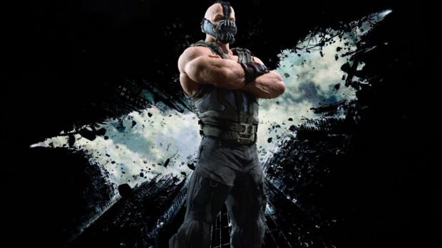 Bane stands with crossed arms in front of a shattered bat symbol background