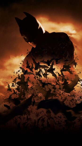 Dark silhouette of Batman surrounded by flying bats against a cloudy sky