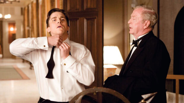 Bruce Wayne from Batman Begins tying a bow tie in a formal setting