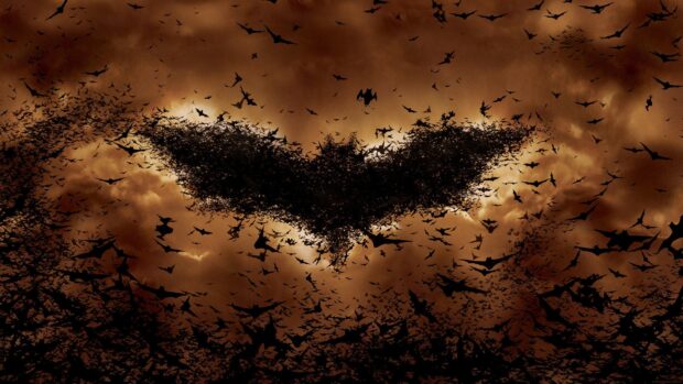 A swarm of bats forming the shape of the Batman symbol in the sky at dusk