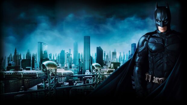 Batman Begins stands in front of a futuristic cityscape with a misty blue sky background