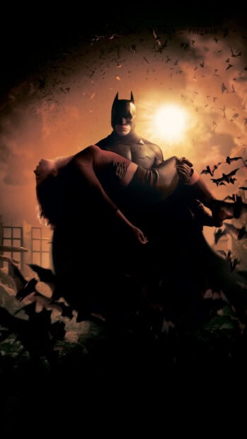 Batman Begins holding a woman with bats flying around in a dark Gotham setting