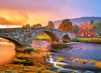 A stone bridge over a flowing river with autumn trees in Wales, HD Desktop Wallpaper