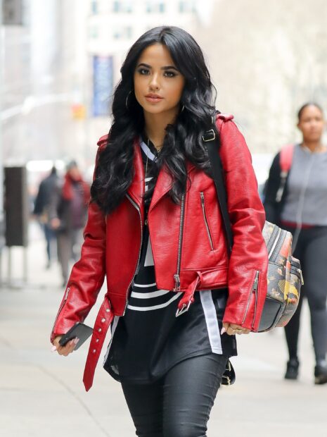 Becky G wearing a red leather jacket walking down a city street with long black hair