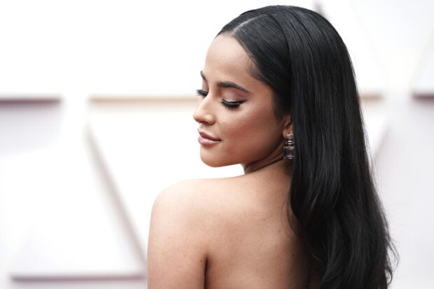 Becky G wearing elegant earrings with long black hair looking down gracefully