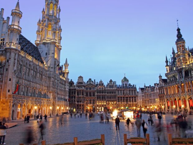 The Belgium city square with historic architecture and people walking at dusk
