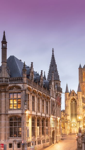 Gothic architecture in Belgium cityscape during twilight with illuminated windows