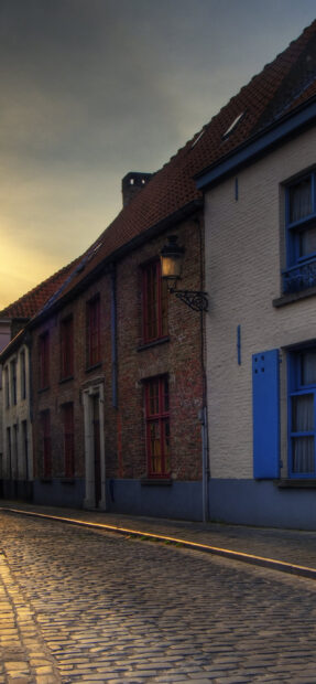 Historic Belgium street with cobblestone and old brick houses at sunset