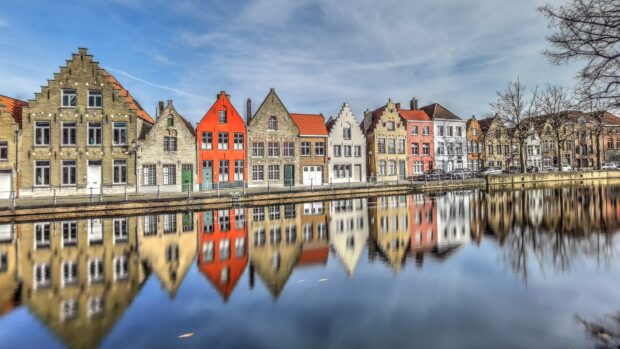 A row of colorful Belgium houses reflected in a calm canal in Belgium