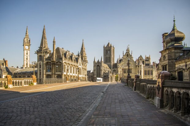 Historic Belgium architecture and cobblestone street under clear blue sky