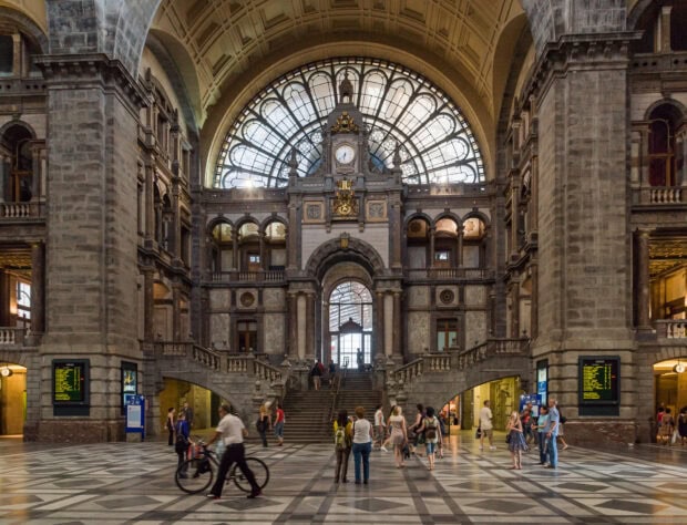 The interior of Belgium central station with travelers walking inside the historic building