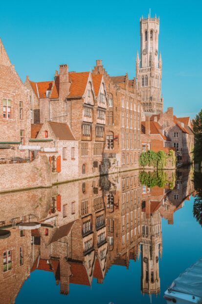 Historic Belgium cityscape with medieval buildings and tower reflected in canal water